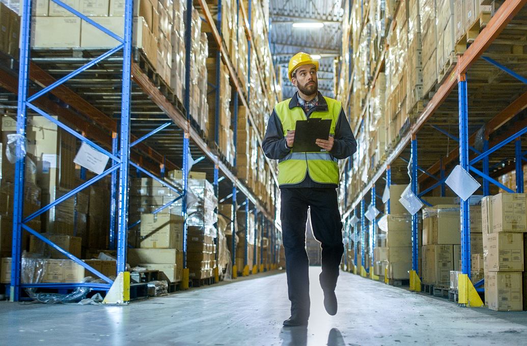 Man walking in warehouse with clip-board