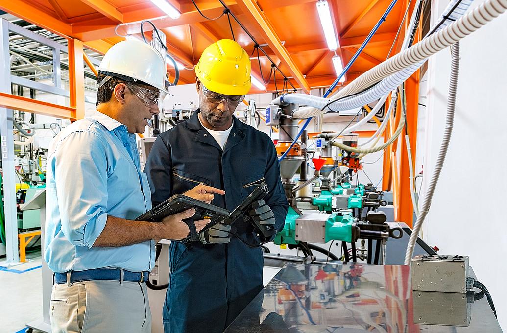 two men in hard hats looking at computers and scanner guns